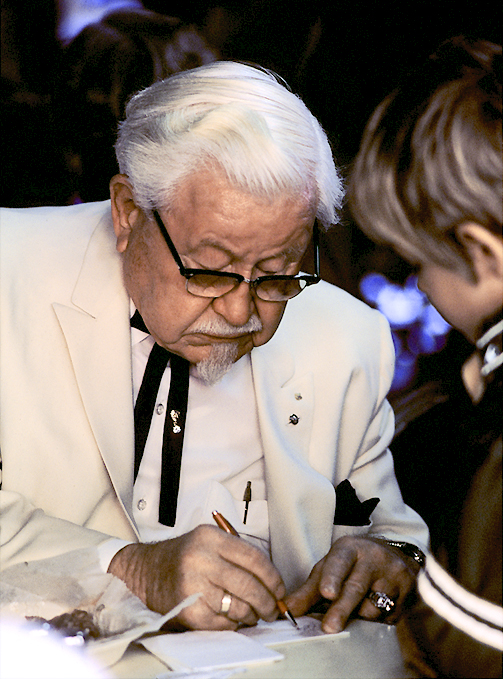 Colonel Harland Sanders in his white suit and string tie.